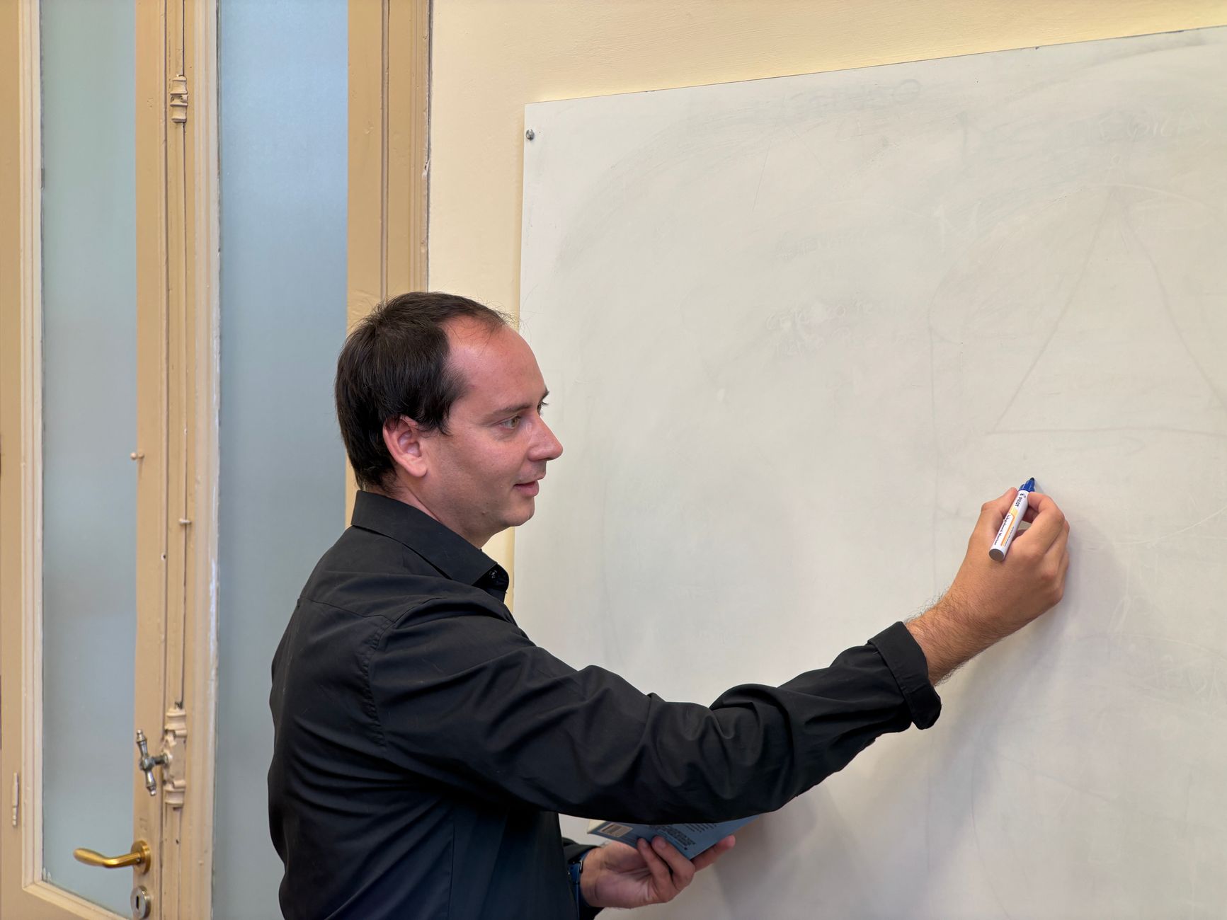 Docente explicando en un tablero a un grupo de adultos